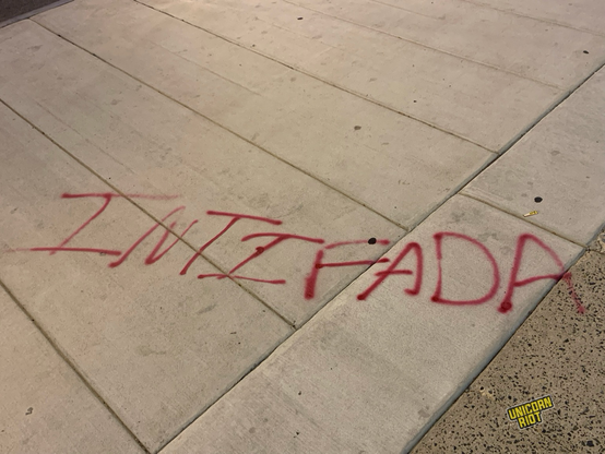 “Intifada” spray painted in red on a sidewalk