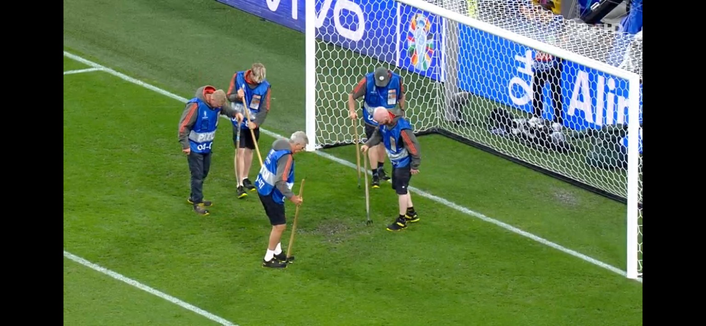 5 groundsmen repair the ground in front of a goal on the pitch at the Signal Iduna Stadium in Dortmund during an unofficial break because of a big thunderstorm 