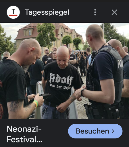 Ein Foto vom Tagesspiegel vom neonazi Festival in ostritz. Sehen ein alter Mann mit einem T-Shirt. "Adolf war der beste" umringt von einigen Fotografen und Polizei. 
Ostritz 
Wo tausende Neonazis mit lauter Musik ihr Nazi sein  feierten und junge Leute rekrutierten.