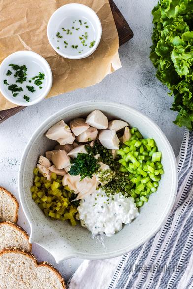 All ingredients (except the bread) for cottage cheese chicken salad are in a mixing bowl, unmixed.