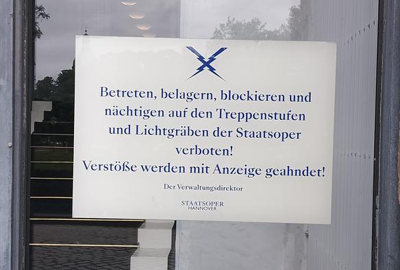 Eins von mehreren Verbotsschildern an der "Staatsoper Hannover": "Betreten, belagern (!), blockieren und nächtigen auf den Treppenstufen und Lichtgräben der Staatsoper verboten! Verstöße werden mit Anzeige geahndet! Der Verwaltungsdirektor, Staatsoper Hannover".