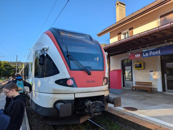 Un Flirt 523 en gare du Pont dans la vallée de Joux. À gauche on aperçoit le bâtiment de la gare avec l'écriteau CFF.