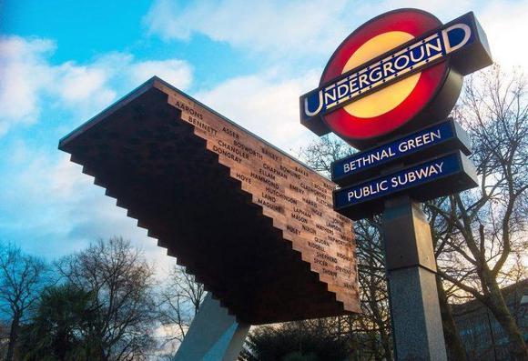Sign
UNDERGROUND
Bethnal Green
Public Subway
Seen against blue sky with white clouds.
Next to entrance is upside down brick “stairway to heaven” memorial with names of those who died on the bricks.