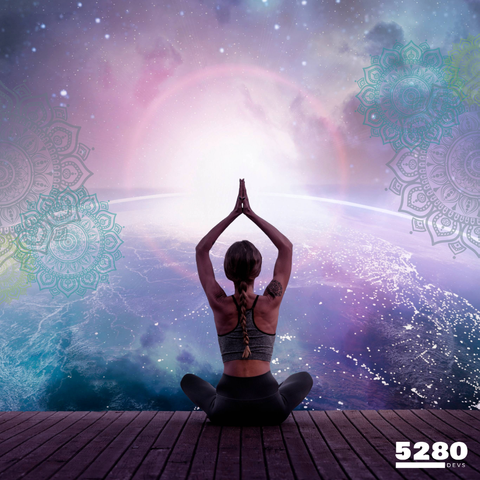 A woman is sitting on the edge of a boardwalk in a meditation pose, with arms held up to the sky.