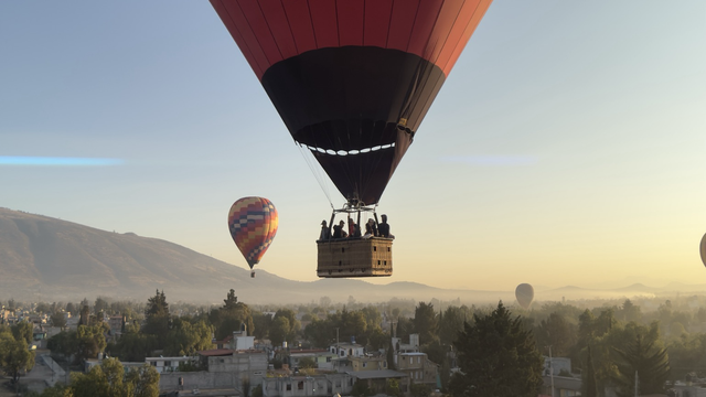 One close centered  hot air Ballon in the middle of the picture surrounded by three other balloons with a wider distance. The photo was taken during the sunrise close to Mexico City on top of the archeological side San Juan Teotihuacán.