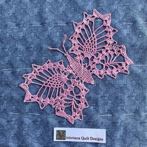 Pink crocheted butterfly, on blue butterfly fabric. 