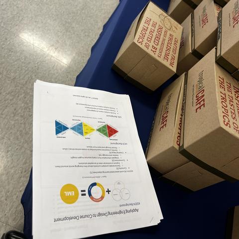 Handouts and box lunches placed on a table with a blue tablecloth. 