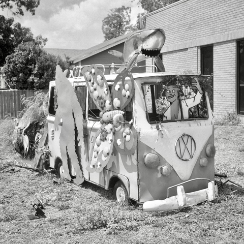 A black and white film photo. A Volkswagen van, Sasquatch, butterfly, shark and human hang out in this custom metalwork creation in San Angelo, Texas. Sunday, September 1, 2024.