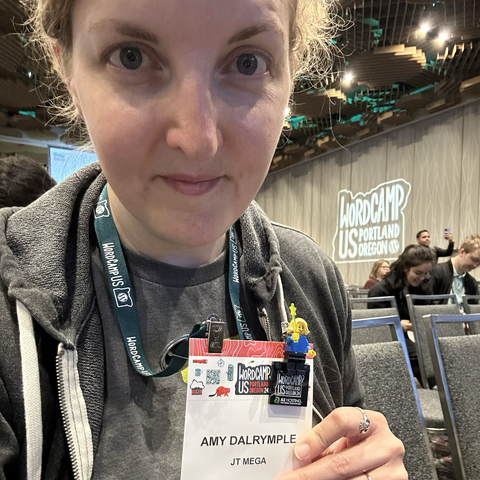 A selfie while waiting for morning keynotes, showing off my new LEGO minifig that I can attach to my conference badge.
