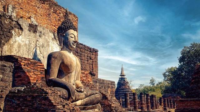 Buddha statue with stupa in background.