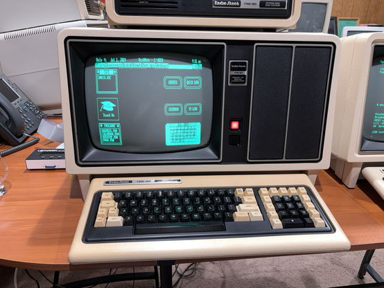 TRS-80 Model 12 computer showing a picture of the Tandy DeskMate 3 desktop from the PC version of DeskMate.