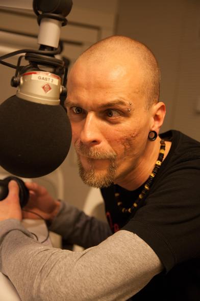 Portrait von Carsten Lehmann aka ohrchitekt im alten radio x Studio. Carsten trägt ein schwarzen Shirt ind schielt auf das Mikrofon, dass vor seinem Kopf hängt! 