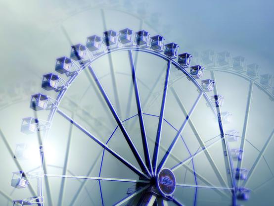 Aufnahme der oberen Hälfte eines großen Riesenrades auf einem Jahrmarkt mit verschiedenen Mehrfachbelichtungseffekten. 
