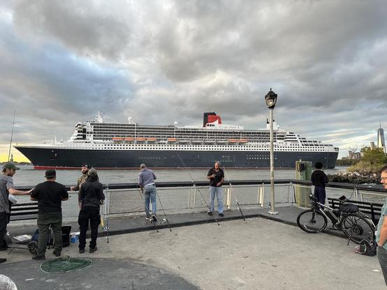 Photo showing the entire length of the RMS Queen Mary 2, just a couple hundred yards away off of Valentino Pier in Red Hook. Just visible ahead of the bow is the Statue of Liberty while just aft is 1 WTC.