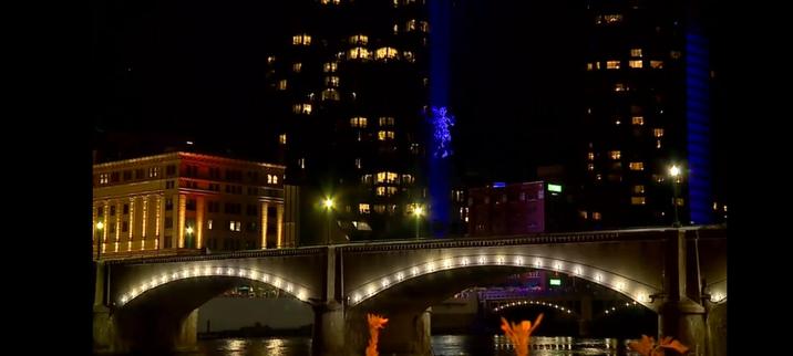 A wide shot of 'David', a 35-foot tall 200-pound puppet, climbing the glass outer walls of the Amway Grand Hotel, in Grand Rapids, Michigan