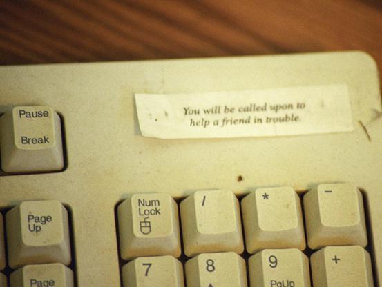 An old computer keyboard with a note saying, "You will be called upon to help a friend in trouble," placed above the keys.  Answer the Call.