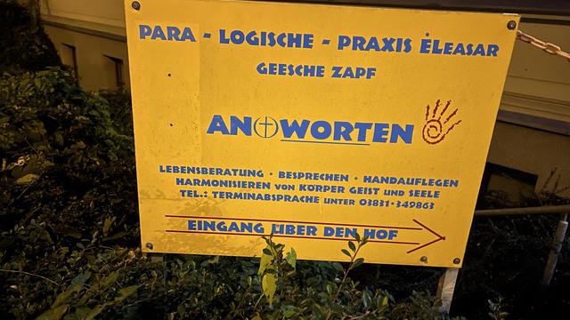 Gelbes Schild einer Schwurblerpraxis mit Handauflegen und Co