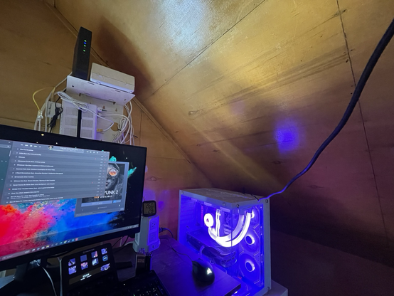 A gaming PC setup in a wooden loft, a cable trails from the computer up and out of frame