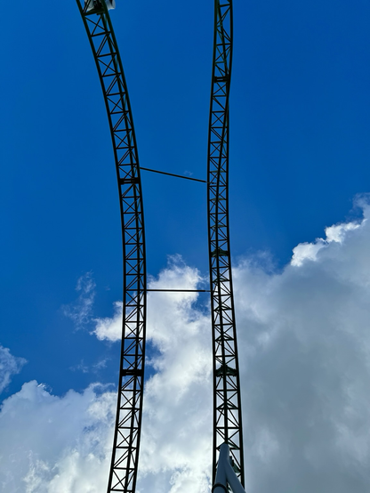 Green track of Junker against a part blue, part cloudy sky. The photo is pointing straight up at the top of the Finnish Loop element - a twisted dive followed by a vertical loop.