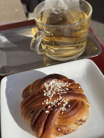 Photo of a Swedish Kanelbulle (cinnamon roll) and a cup of tea.