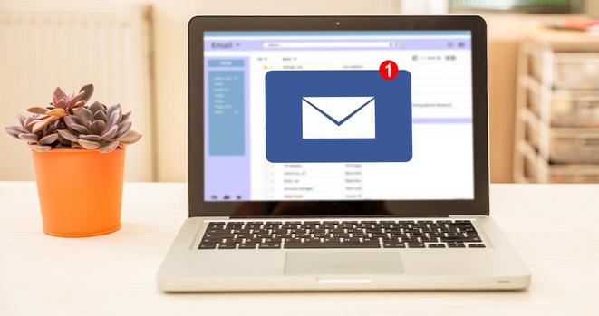 Email message inbox on computer laptop screen on a white office desk. 