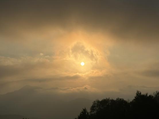 Puesta de sol en las montañas, cielo de nubes blancas teñidas de naranja.
