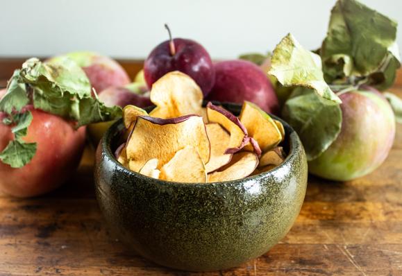 A photo of apple chips in green bowl.