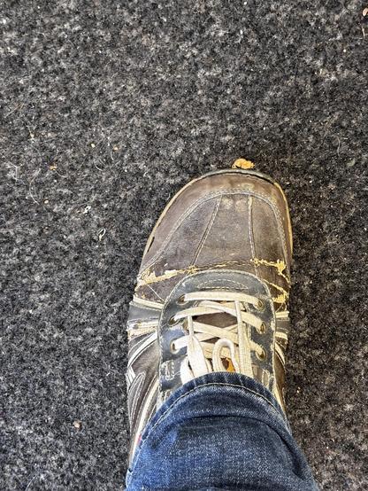 Kaputte Schuhe. Oberleder platzt ab. Sohle löst sich. Links und rechts Löcher an den Seiten. Löcher vorne.