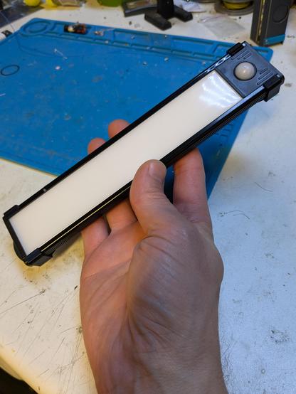 A long thin Led strip PID light held in the hand on a work bench 
