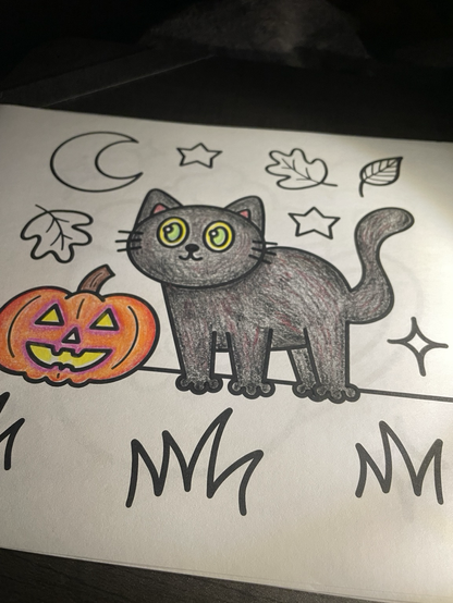 Coloring page (by Rana Awadallah) partially colored in of a black cat, jack o’ lantern, autumn leaves, stars, and crescent moon