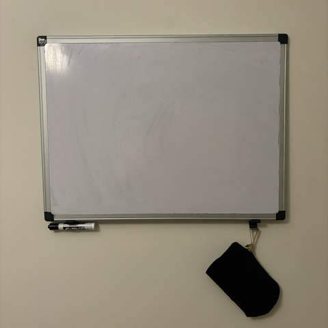 A whiteboard on a wall with two supports below holding a marker and an eraser