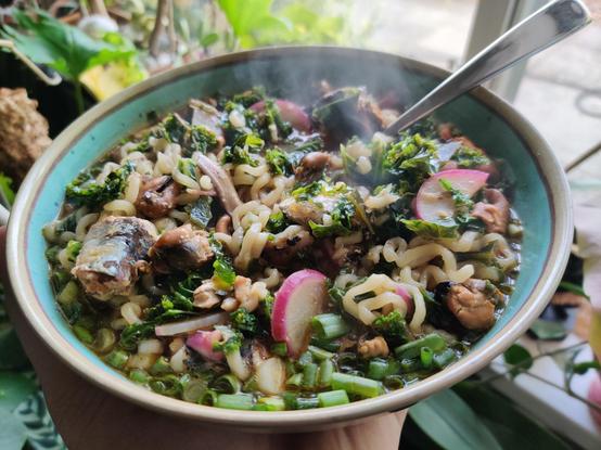 A bowl of steaming noodles, with lots of tasty veggies and seabeasts poking out to say hi.