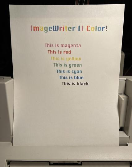 A letter size page on an ImageWriter II sheet feeder that says ImageWriter II Color! in rainbow colors followed by “This is” and a color name on each line for magenta, red, yellow, green, cyan, blue, and black in that color. 