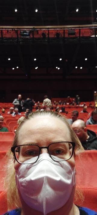Frau mit Maske in Theater mit rotem Plüsch