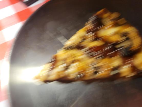 A blurry slice of mushroom & truffle oil pizza on an aluminum plate