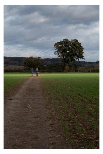 Footpath in Henley on Thames with sun rays highlighting the people standing on the path. 
