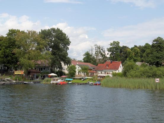 A boat rental service at the side of the lake. A small marina with several small boats moored.