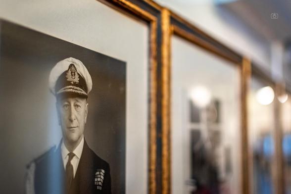 A row of brass framed black and white portraits of the admirals who had commanded the now retired royal yacht, which is now a floating museum. HMY Britannia, Leith, Edinburgh, 20 Aug 2024. Nikon D5600, Nikkor DX 35 mm ƒ1.8G, ISO 640, ƒ1.8, -0.3 ev, 1/80s