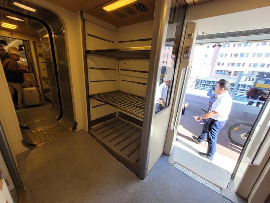 Entrance luggage space space, with staff checking tickets and a bicycle wheel visible on the platform.