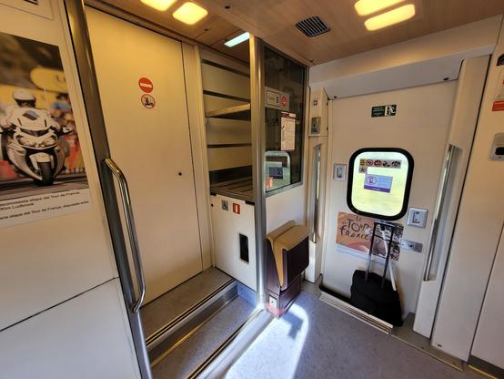 Last door of the train, with a no-way door towards the driving car. Empty small luggage rack. Tour de France picture exhibition.