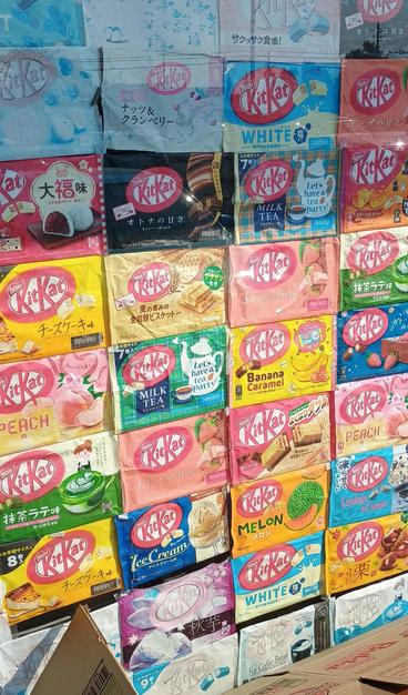 A window display shows KitKat chocolate bars with many different flavour options