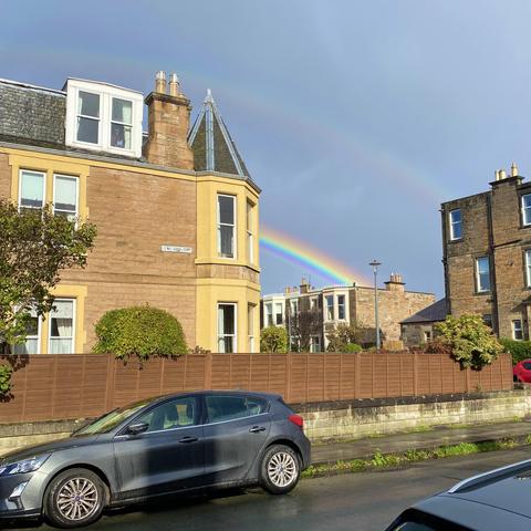 Very bright rainbow edge behind terraced houses, faint double rainbow