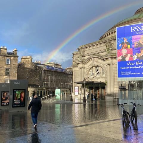 Guy walking into a rainbow in front of Usher Hall