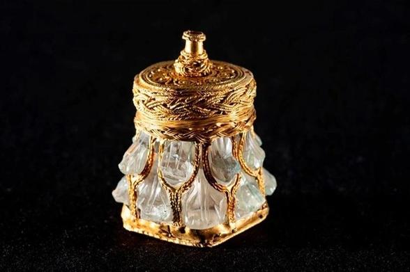 Tarro de cuarzo tallado como hojas, entre las cuales pasan finas cuerdas de oro. La tapadera y la base son de oro, con detalles en forma de cuerdas entrelazadas.