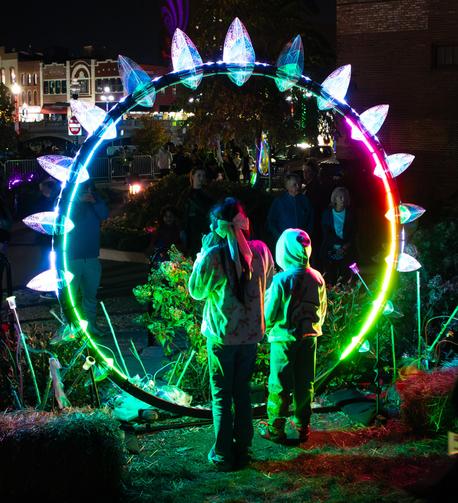 Two children posing for a photo (not this photo) in the center of a ring of colored light at Lumenaura.