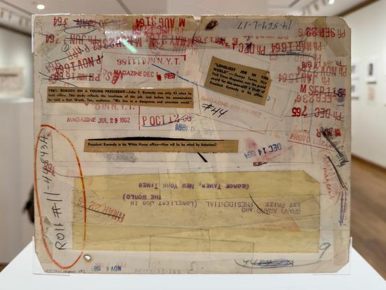 Press markings in grease pencil, red stamp, and yellow post-it notes on the back of the JFK photo.