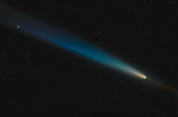 Comet with blue tail and orange core in the night sky