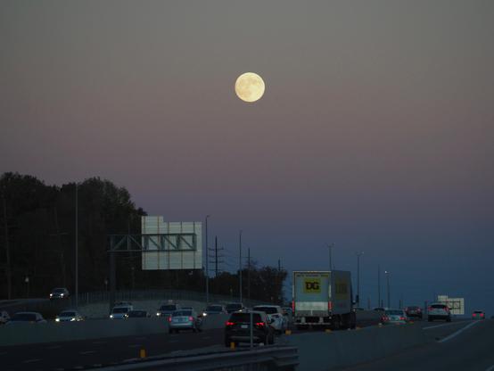 A nearly-full moon, seen above the interstate.