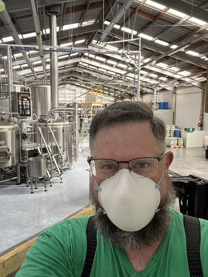 Head Brewer (wearing a dust mask) mid-milling looking out at our brewery from the camera POV.