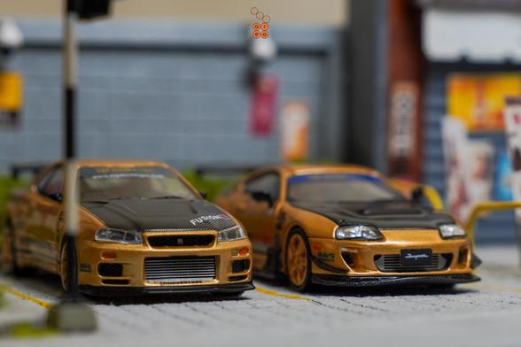Nissan Skyline GT-R (R34) Top Secret Gold by MINI GT and Toyota Supra (JZA80), Top Secret Gold by Time Micro in 1:64 scale on AREA 164